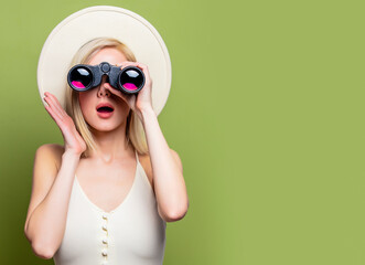 Beautiful blonde girl in a white hat and dress with binoculars