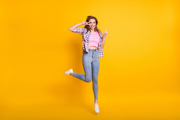 Fototapeta na wymiar Full length body size view of pretty cheery girl jumping showing v-sign having fun isolated over bright yellow color background