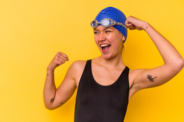 Young swimmer venezuelan woman isolated on yellow background raising fist after a victory, winner concept.
