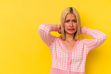 Young venezuelan woman isolated on yellow background touching back of head, thinking and making a choice.
