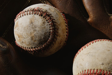 Grit of sport shows old used baseball balls with ball glove background.