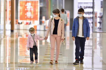 Mom and children wearing face masks walk through the shopping center during the COVID-19 pandemic.