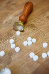 Vintage wax seal stamp lies on a wooden table. Golden spoon and pieces of wax