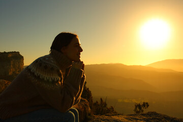 Woman silhouette meditating at sunset in the mountain