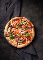 Delicious pizza with bacon, mozzarella, cherry tomatoes and mushrooms on a dark background, vertical orientation, flat lay