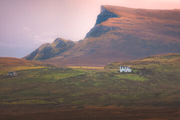 Dramatic countryside mountain landscape at sunset or sunrise of a lone croft house on farmland at Kilmaluag on the Isle of Skye in the Scottish Highlands.