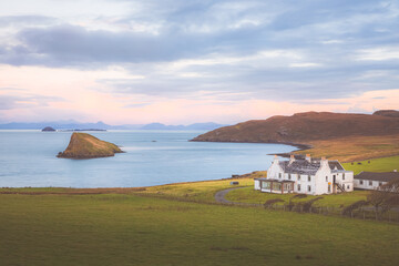 Idyllic coastal seaside view at sunset or sunrise of a rural,  country farmhouse in Duntulm on the Isle of Skye coast in the Scottish Highlands.