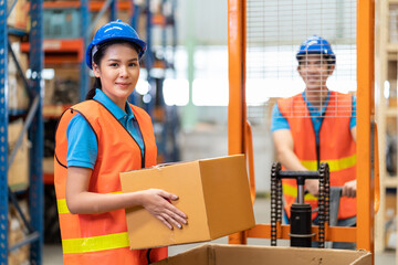 Group of Asian young male and female employee warehouse worker in safety vest and helmet moving or...