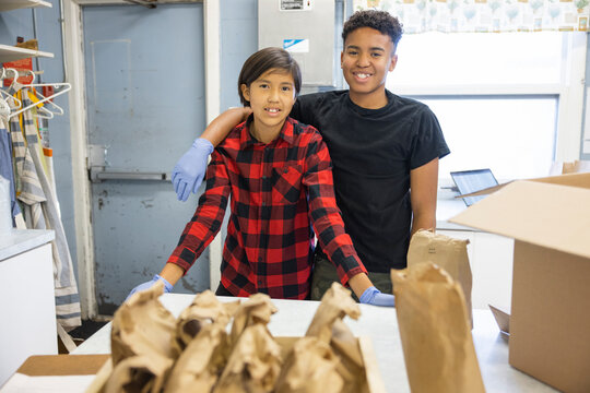 Portrait happy teenage volunteers in community center kitchen