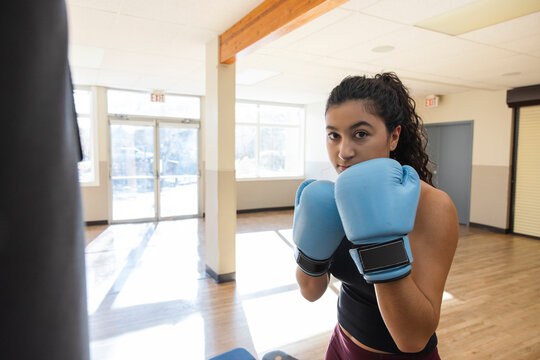 Portrait confident determined teen girl in boxing gloves at gym