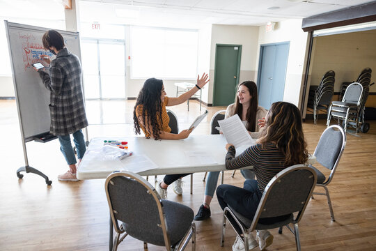High school girl students rehearsing script at table in drama class