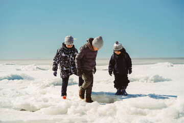 children walking on ice piling of finland gulf. boy slump under ice cake. image with selective focus