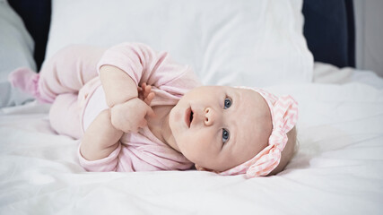 infant baby girl lying on bed while looking up.