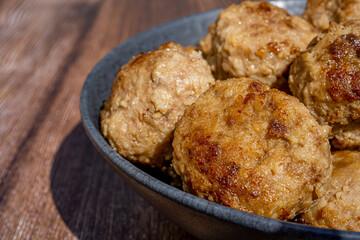 Minced meat ball in black plate, selective focus. Homemade cutlets on a wooden background in rustic style with copy space. Top view, flat lay