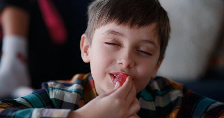 Sugar addiction. Young naughty kid boy eating many candies closing eyes of satisfaction enjoying...