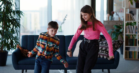 Couple of amazing teenage kids sister and brother dancing in living room into music enjoying entertainment vlogging online for follower broadcast making video. © Fractal Pictures
