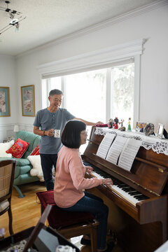 Senior Man Looking At Wife Play Piano At Home