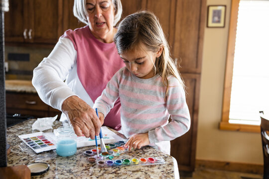 Grandmother and granddaughter painting at home