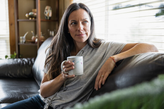 Portrait Of Smiling Woman With Hot Drink On Sofa