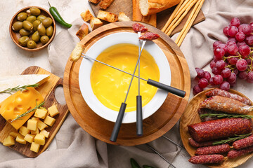 Cheese fondue and different snacks on light background