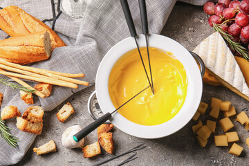 Cheese fondue and different snacks on grunge background