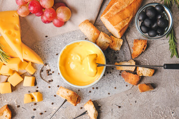 Cheese fondue and different snacks on grunge background