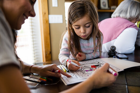 Girl and mother coloring on book