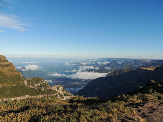 Fototapeta premium Landscape panorama with mountains and clouds flanking a valley. Highlighted the so-called pierced stone. View from the Church Hill, in Urubici, State of Santa Catarina, Brazil.