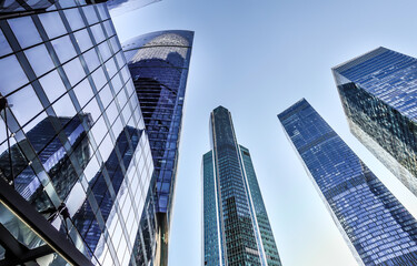 Spiky skyscrapers of glass, staring up into the blue sky. The image is taken from a low angle.