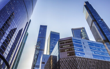 Modern silhouettes of glass skyscrapers of the city business center with a cloudless, slightly blue sky.