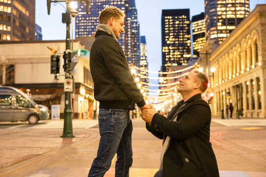 Gay Man Kneeling And Proposing To Boyfriend On City Street At Night