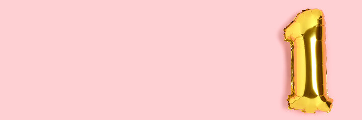 Banner with number 1 golden balloon with copyspace. One year anniversary celebration concept on a pink background. © rorygezfresh
