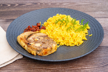 Roasted chicken breasts stuffed with meat, onion, pepper, garnished with curry yellow rice and dried cherry tomatoes. Served on a black plate