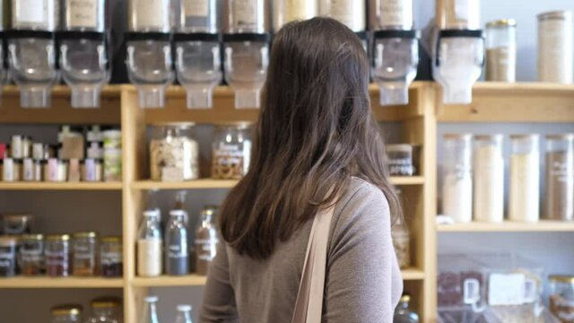 Woman in a mindful consumption store without packaging with pasta, nuts or grains in a store without plastic waste. Low-waste lifestyle. Sustainable ecological lifestyle