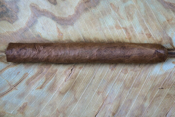 Bodegón que nos presenta un cigarro puro cuya textura más tostada destaca de la de la hoja seca...