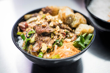 Salade de Nems avec des pat thaïlandaise dans un bol noir dans un restaurant asiatique