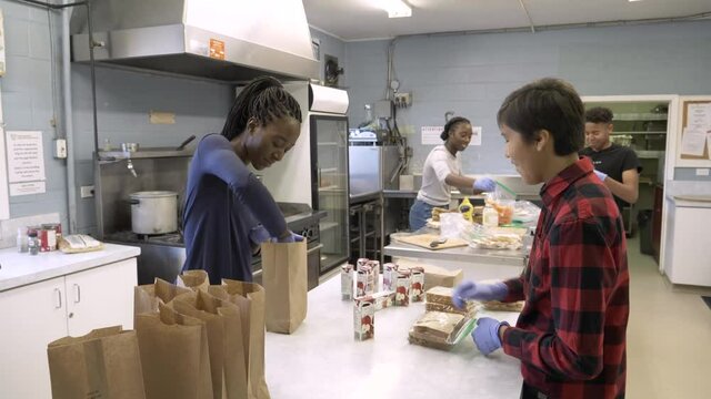 Volunteers Making Bag Lunches In Community Center Kitchen