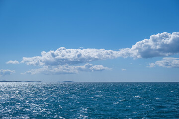 Blue sea and sky background, blue shades and white clouds.