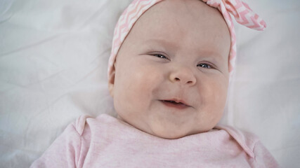 top view of cheerful baby smiling while looking at camera in bed.