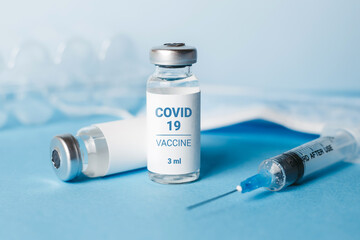 Coronavirus vaccine. Ampoules with coronavirus vaccine and a syringe on blue background. Covid-19 treatment