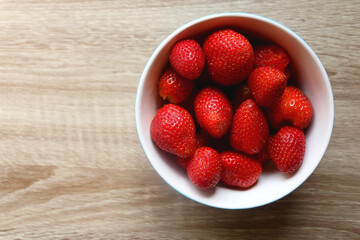 Bowl of fresh strawberries on a table. Flat lay.