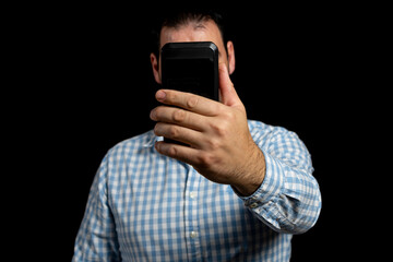 Bearded man in a plaid shirt using a mobile isolated on a black studio background