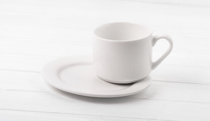 Empty cup standing on plate on white table