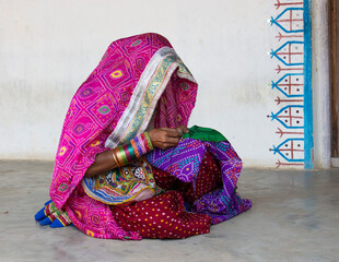 Verhüllte  Frau in Gujarat/Indien beim Sticken vor ihrem Haus © Irmgard