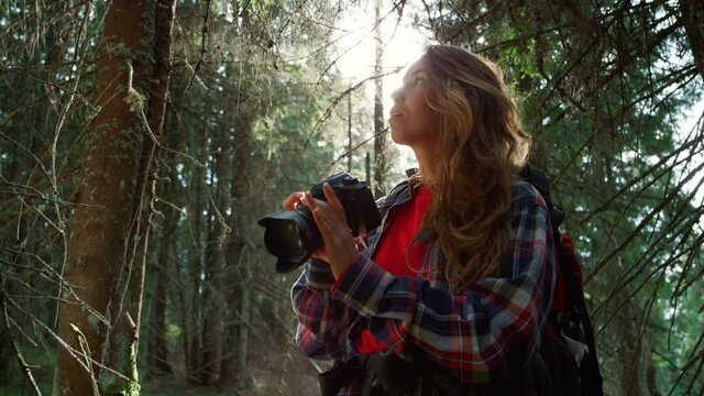 Woman taking photos on camera in forest. Tourist adjusting zoom on camera lens 