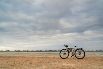 Fototapeta na wymiar spring biking, touring or commuting - bicycle on a lake beach, Boyd Lake State Park in northern Colorado