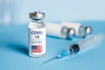 American vaccine concept. Ampoule with injection from covid-19 on a blue background and a syringe