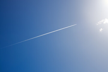 white trail from a military aircraft high in the blue sky, supersonic fighter in flight on a sunny day