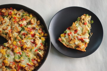 A thin crust homemade pizza loaded with cheese, chicken and vegetables.