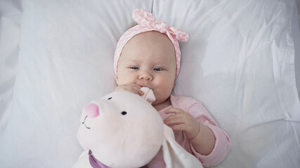 top view of baby in headband with soft toy.